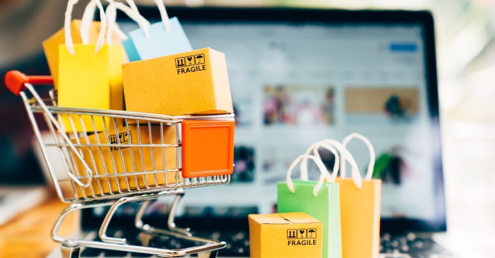 Product package boxes and shopping bag in cart with laptop computer which web store shop on screen for online shopping and delivery concept